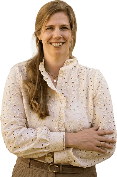 Woman in white embroidered blouse with crossed arms smiling